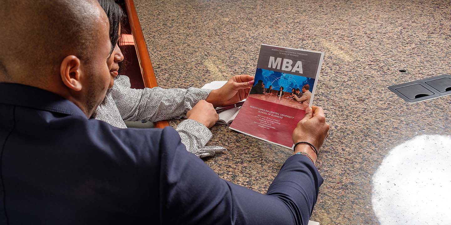 Students looking at MBA booklet.