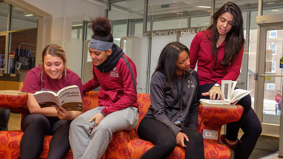 Four NCCU student athletes sitting in the library.