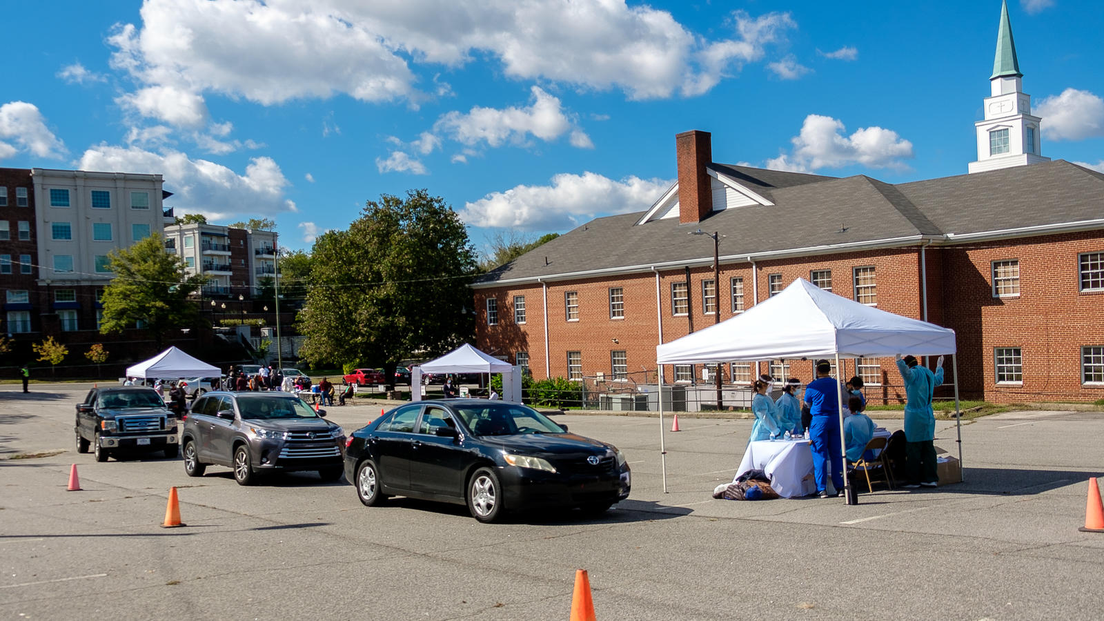 Cars lined up in church parking lot beside tent.