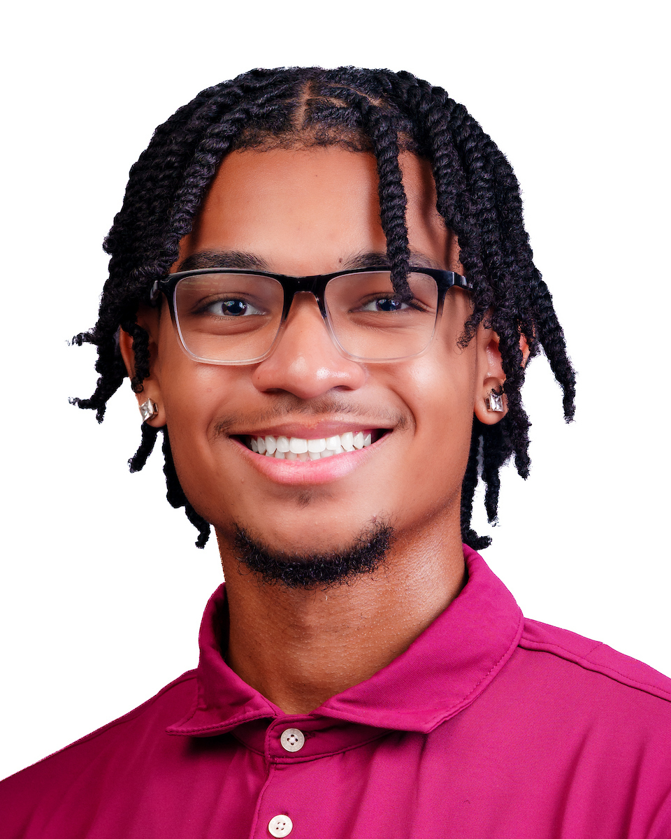 Portrait of a smiling North Carolina Central University Chancellor’s Ambassador Raymond Lomax wearing glasses and a maroon polo shirt.