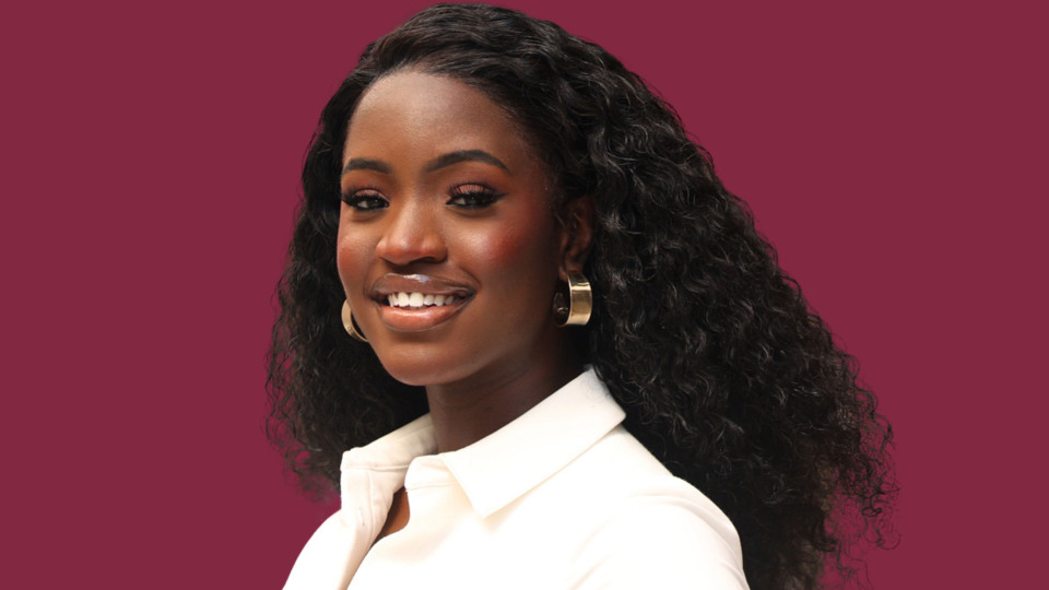 Professional headshot of a smiling Carrie Evertt with long curly hair, wearing a white blouse and gold earrings against a solid background.