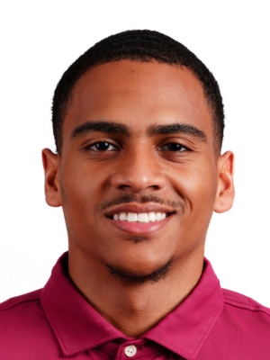 Brayden Smith headshot portrait, smiling professional wearing a maroon collared shirt against a white background.