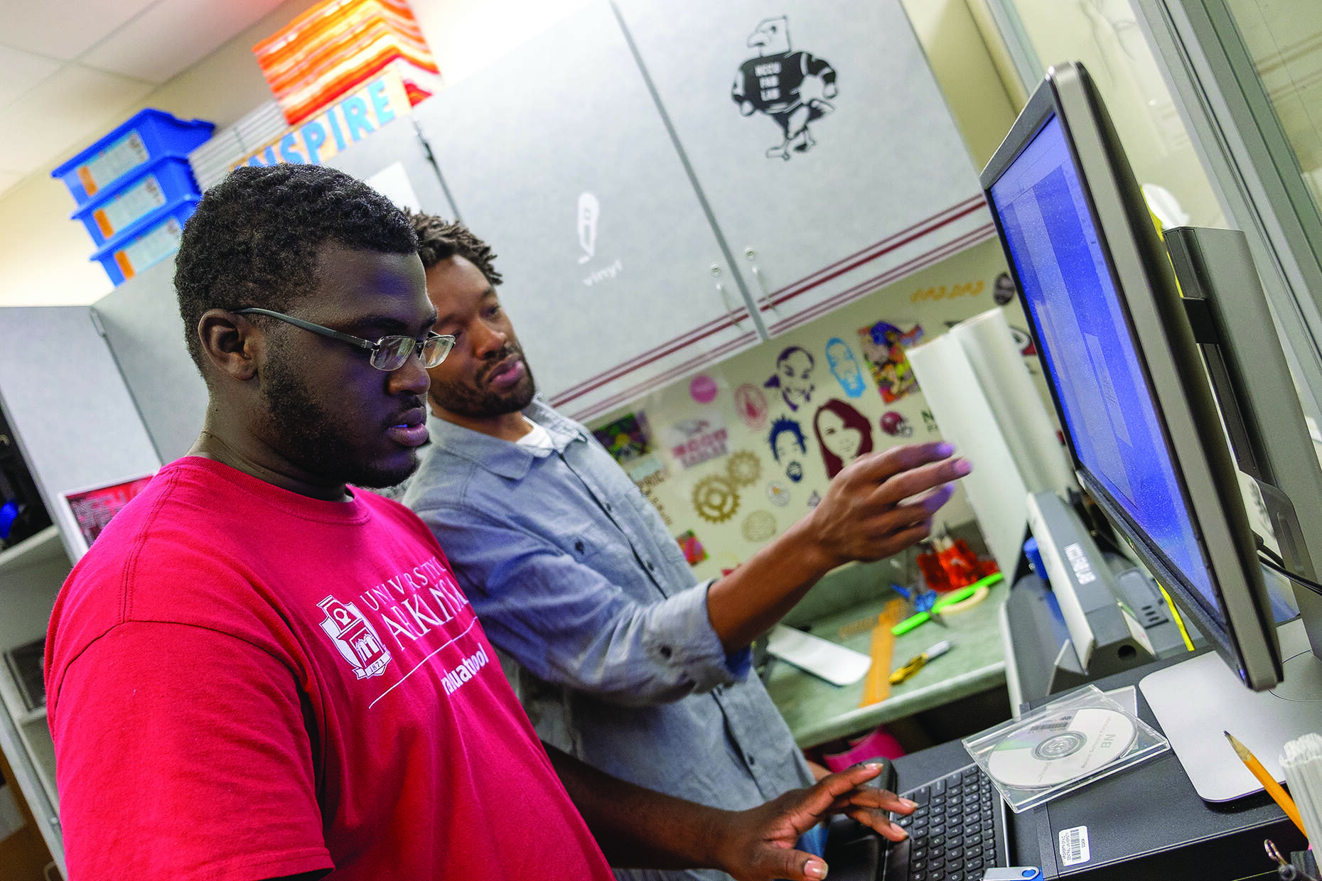 Instructor Eric Saliim looks over a student project in the Fab Lab. 