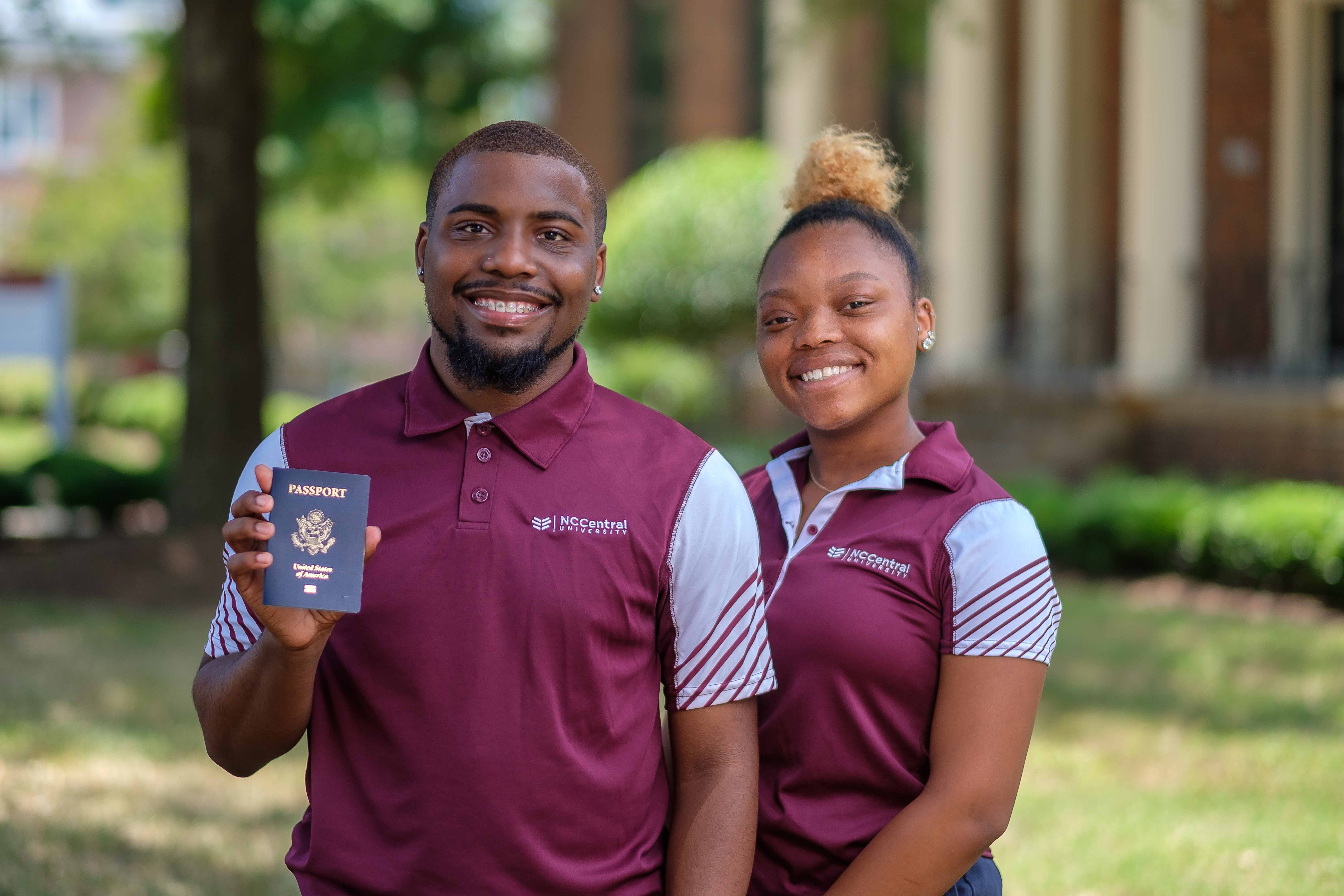 Two students smiling and showing their passport