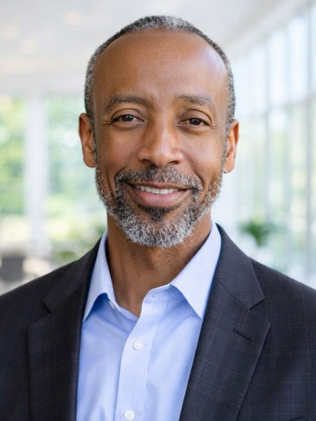 Professional headshot of Charles Johnson, NCCU leader, smiling in a suit inside a bright campus building.