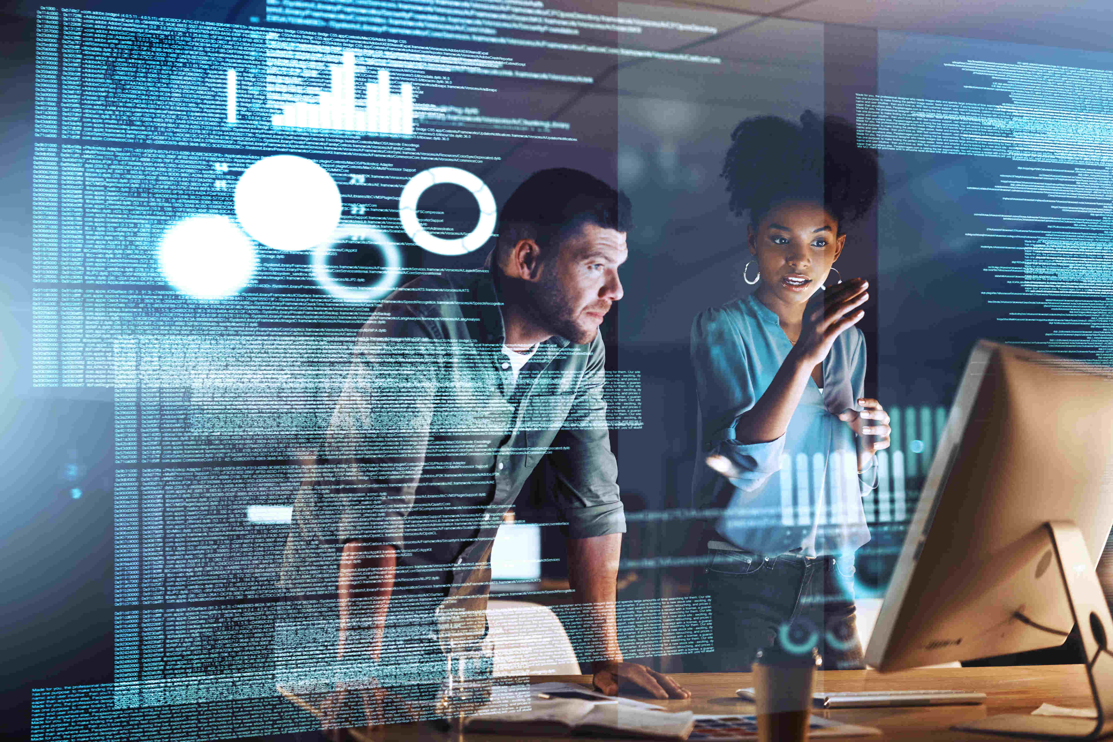 Stock image of a man and woman speaking while leaning over a desk