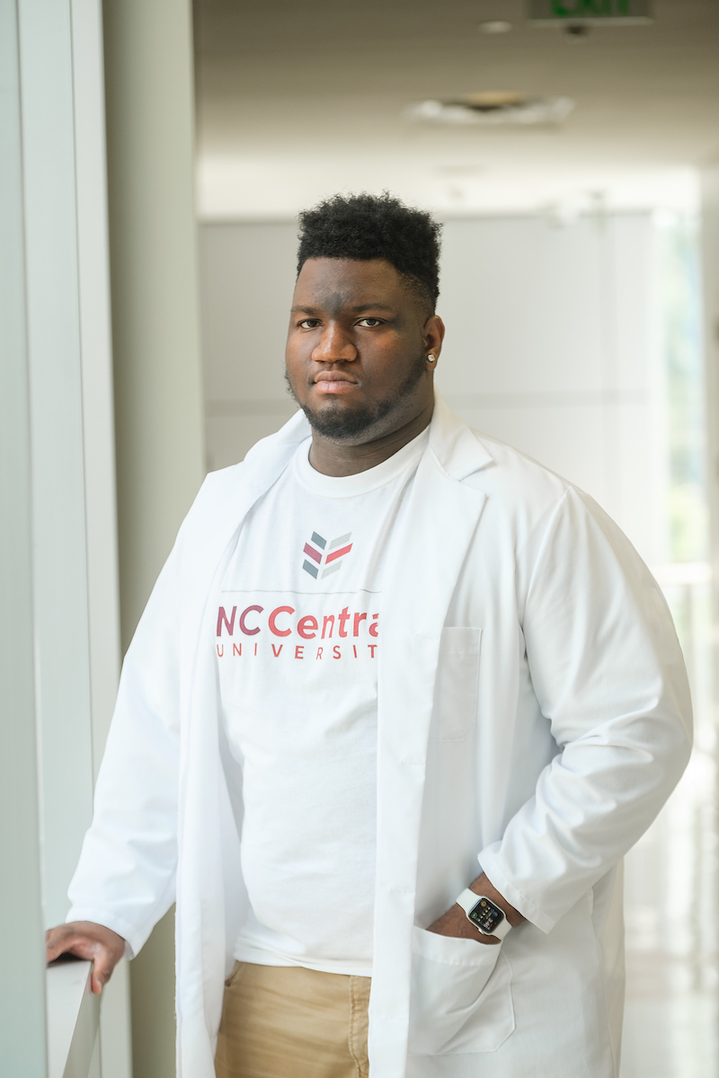 Student in lab coat lookin out the window. 