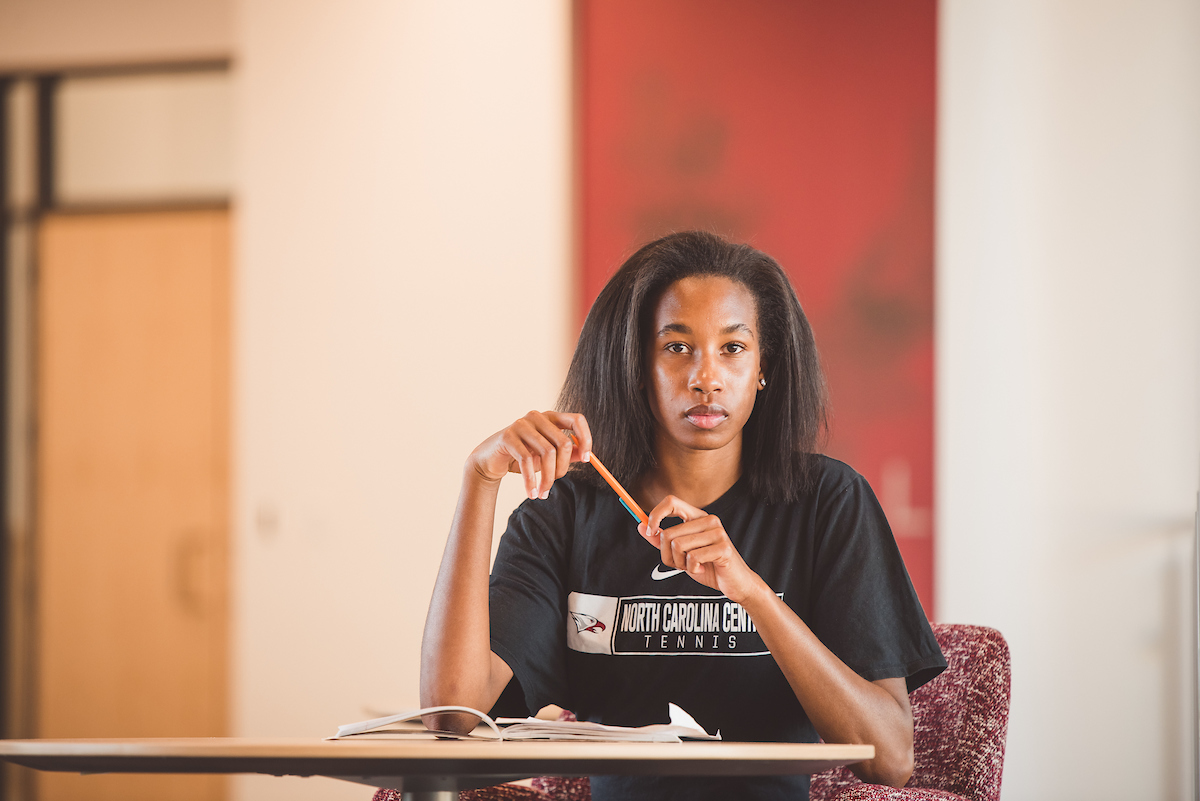 Student at a desk holding a pencil