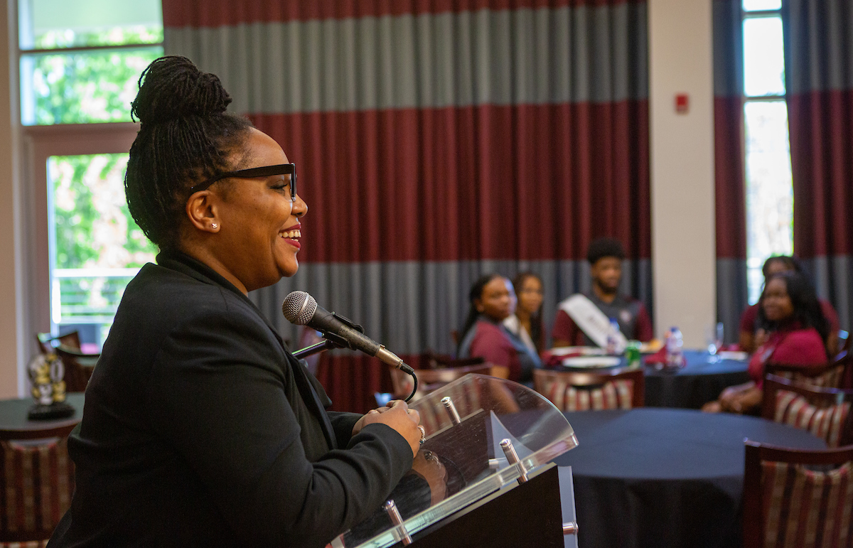 Smiling woman giving a speech to a crowd 