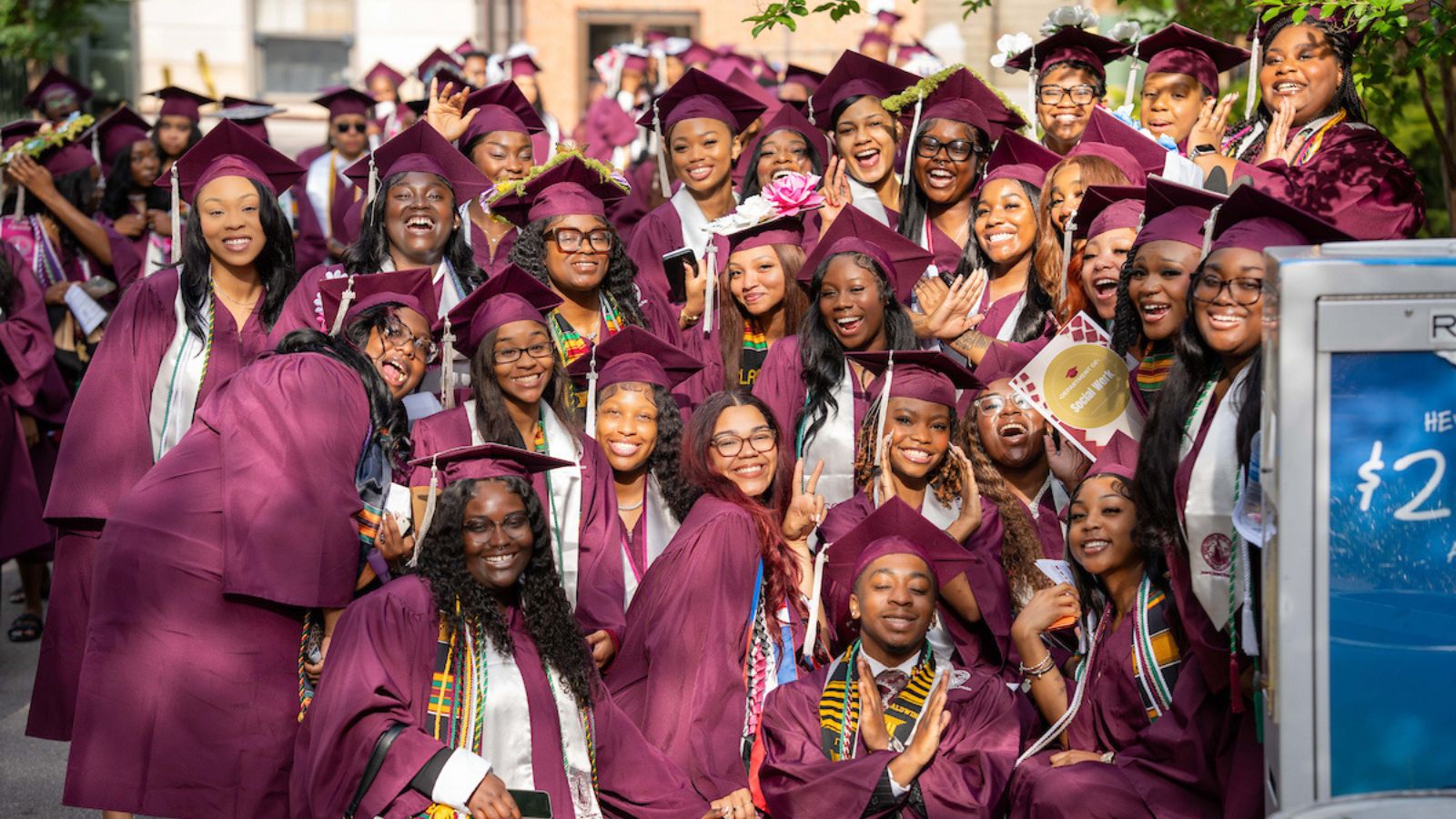 A large group of North Carolina Central University graduates in maroon caps and gowns smile and celebrate together after commencement.