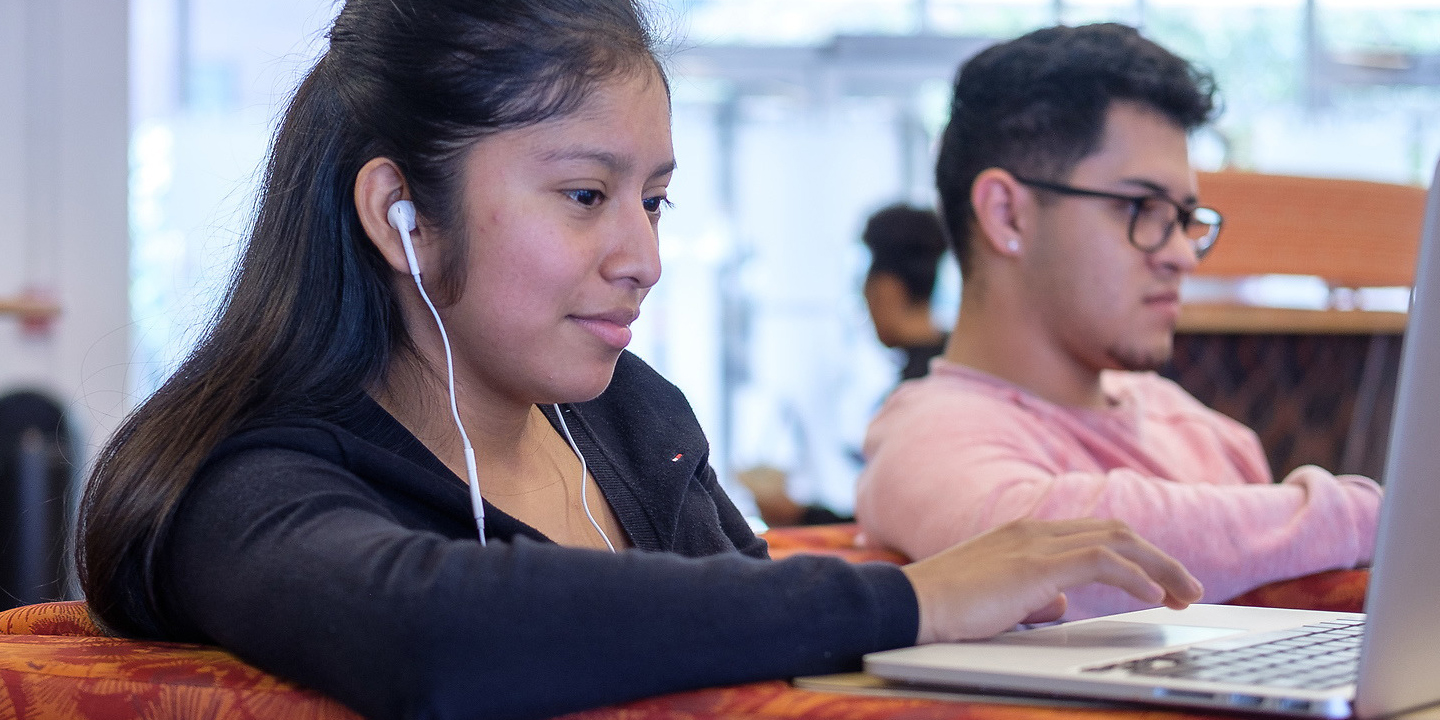 Student sitting in the library on their phone.