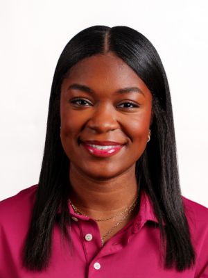 Addie Reid headshot portrait, smiling professional wearing a maroon collared shirt against a white background.