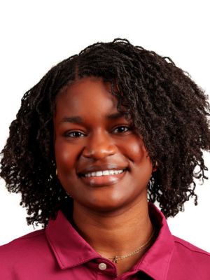 Amara Barnes headshot portrait, smiling professional wearing a maroon collared shirt against a white background.