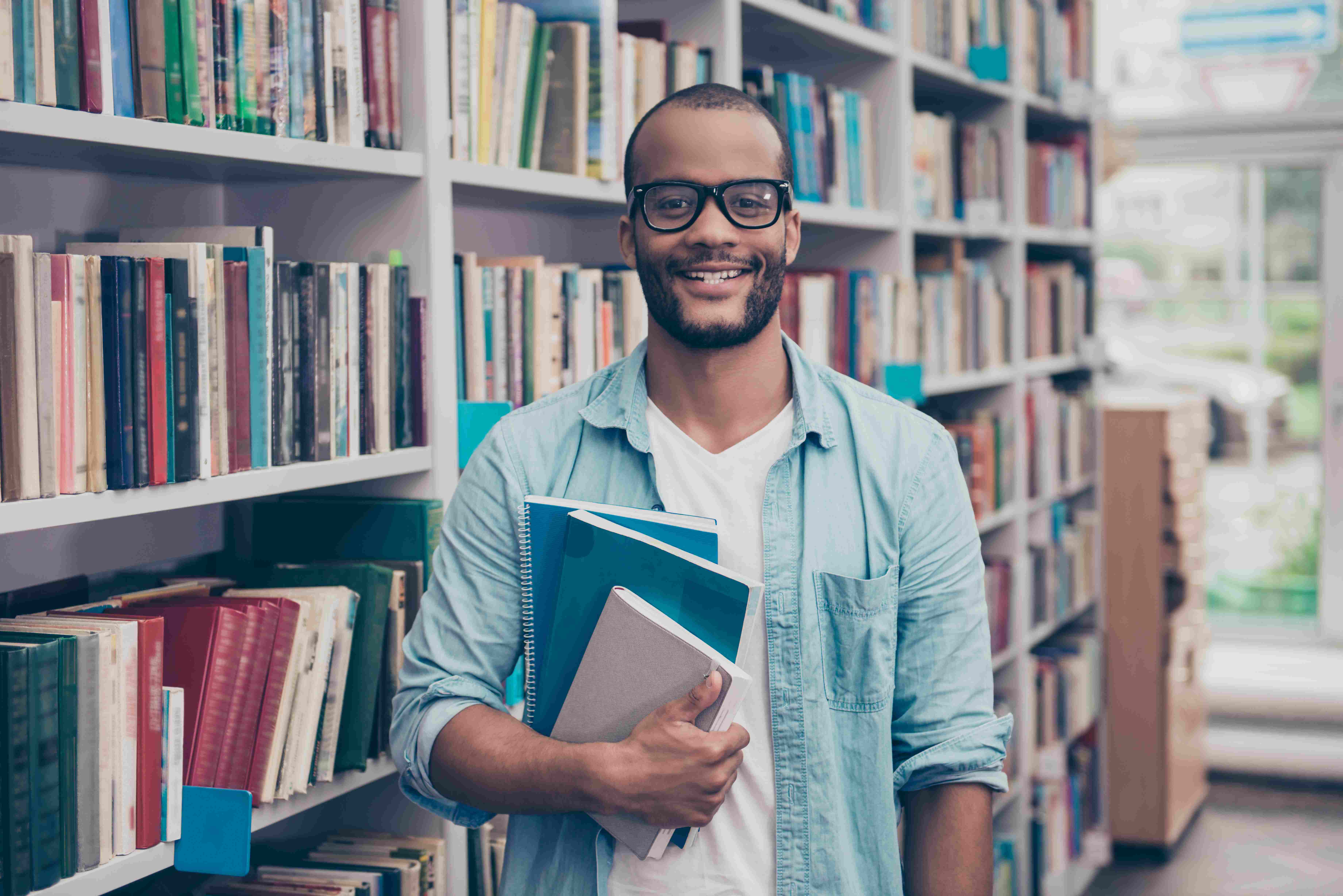 Student standing in library holding books.