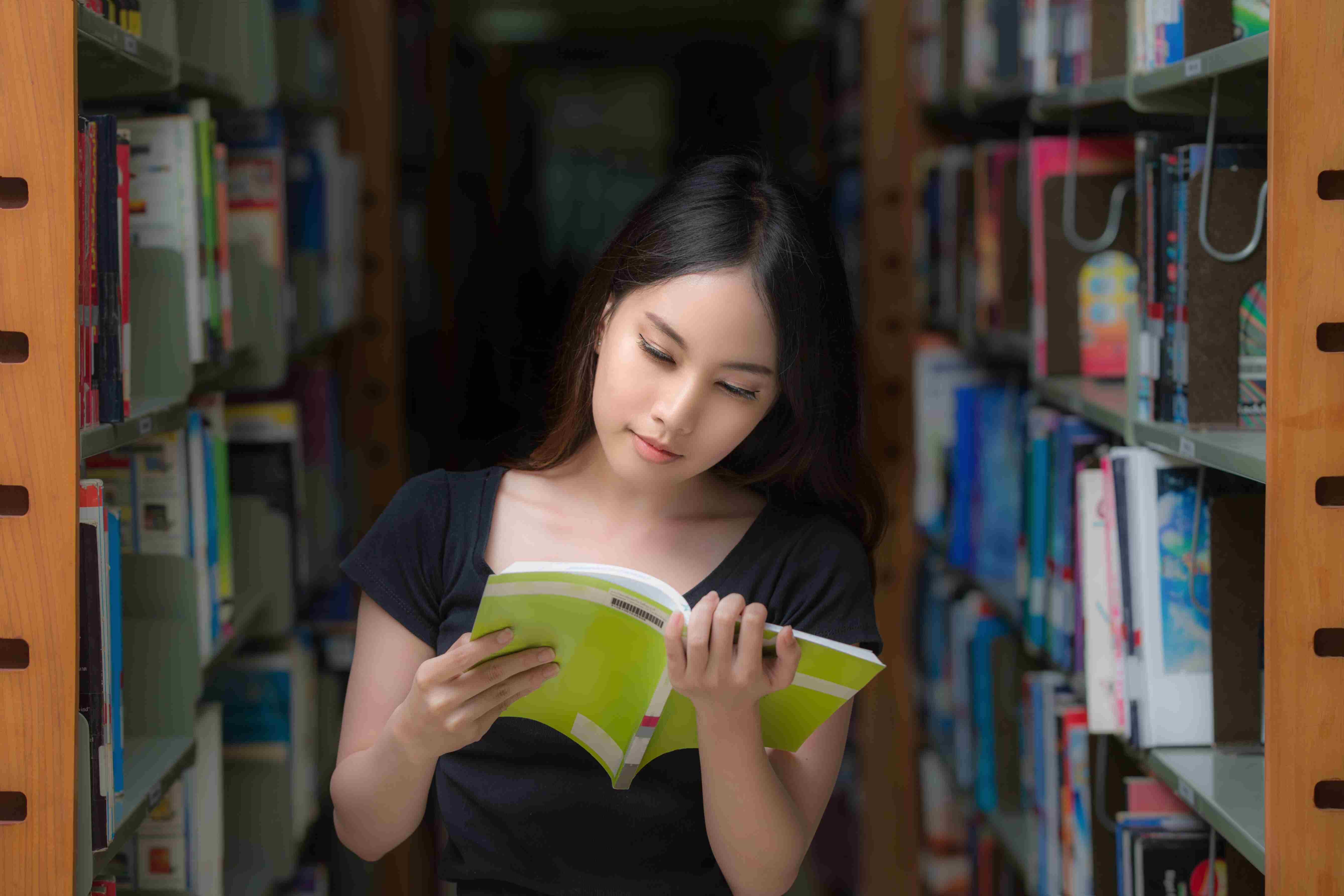 Student sitting in library reading a book.