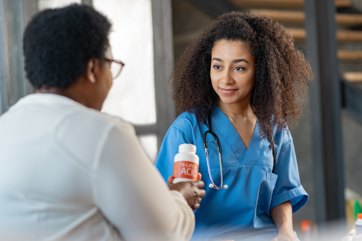 Young Nurse Listening To Pleasant Aged Woman In The Hospital