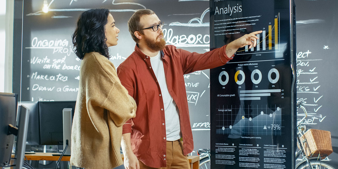 Stock image of 2 people looking at a board.