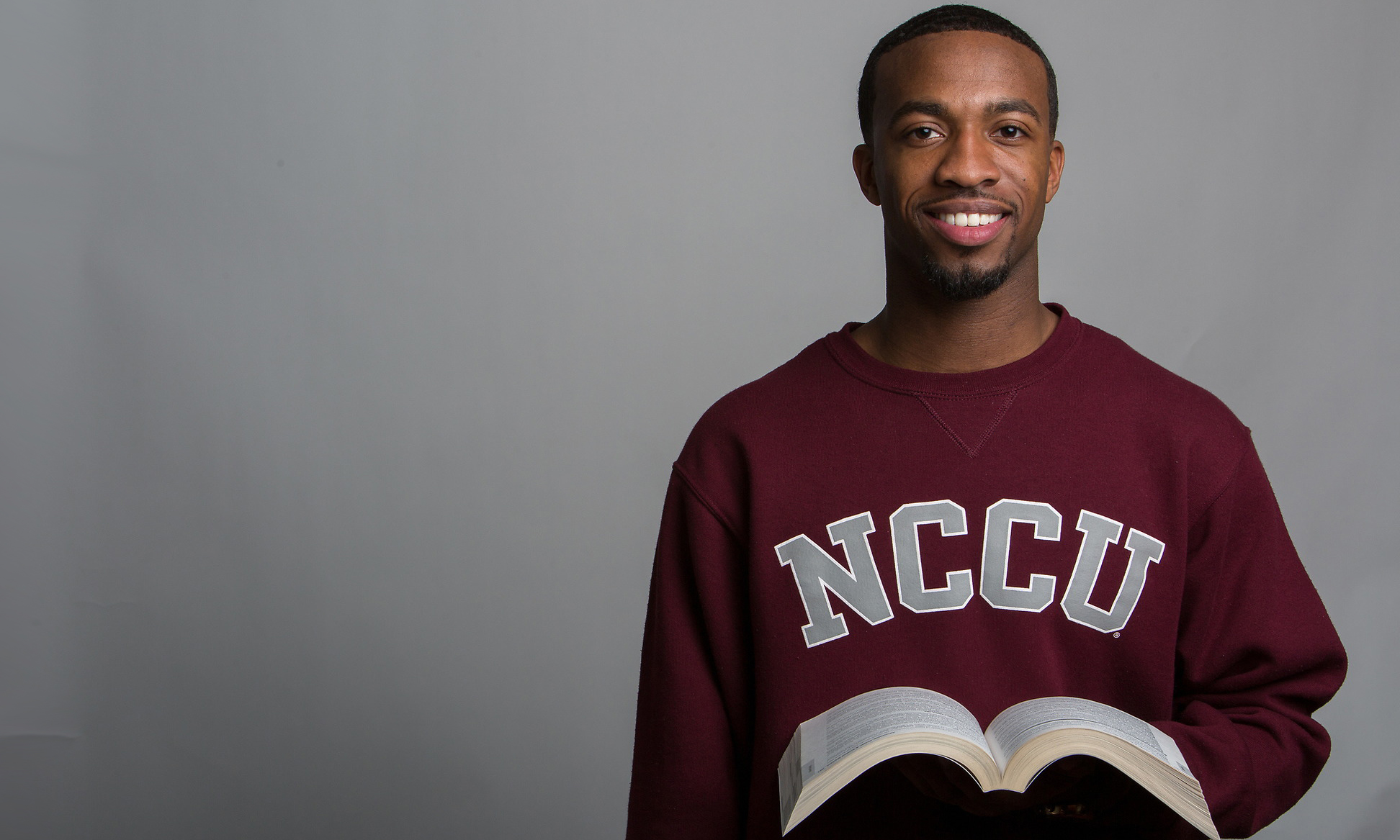 Student standing with a book.
