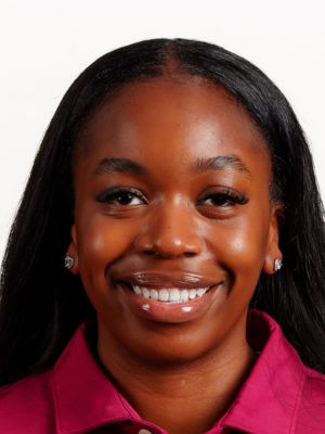 Kendall Smith headshot portrait, smiling professional wearing a maroon collared shirt against a white background.