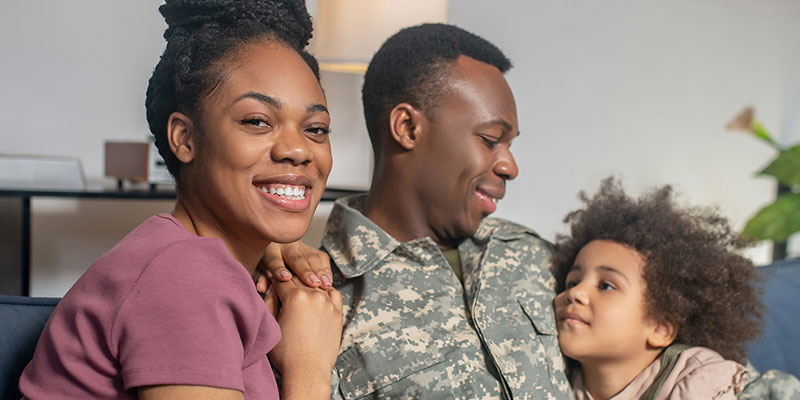 family sitting together. military dad smiling at his son and the wife smiling at the camera
