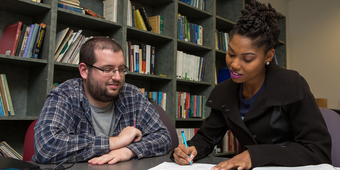 Students sitting at a desk talking.