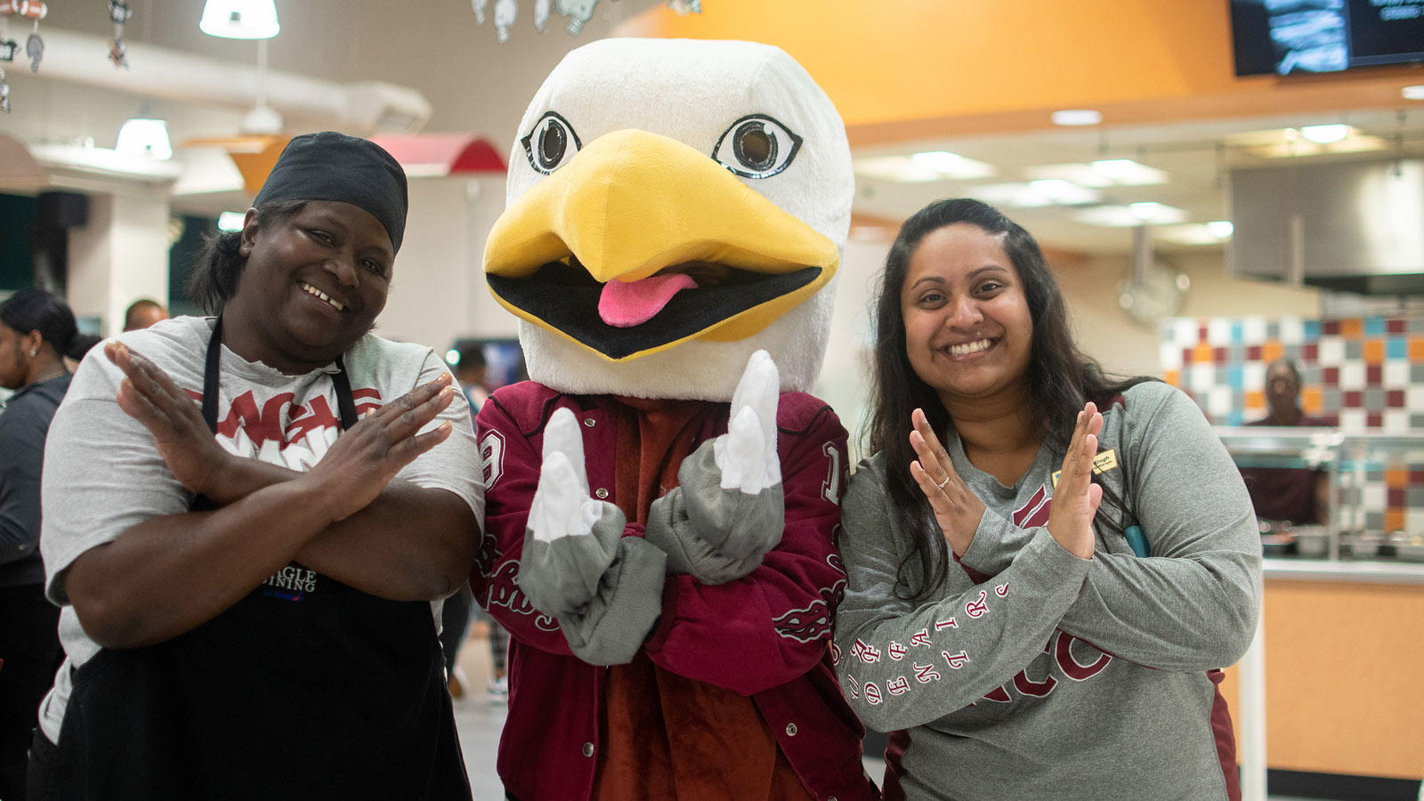 Eddie the Eagle doing eagle hands with two other people