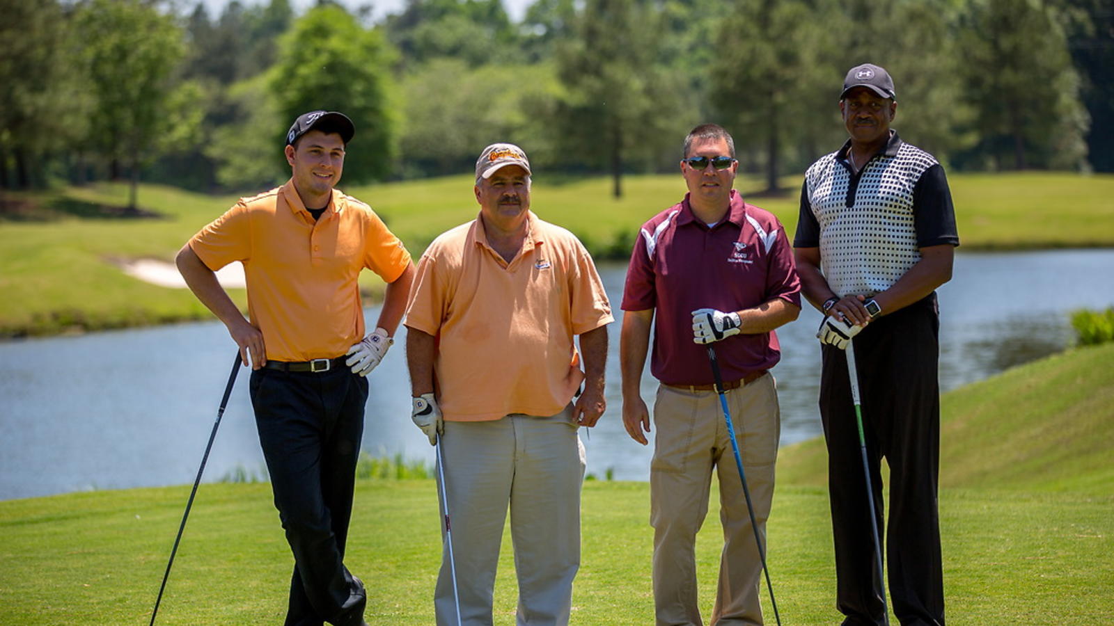 NCCU alumni posing for photo on the golf course, dressed in golfing apparel.