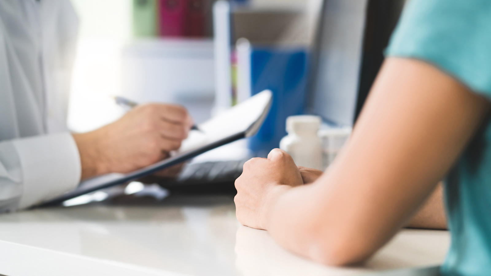 A stock image of a healthcare professional taking notes during a doctor appointment