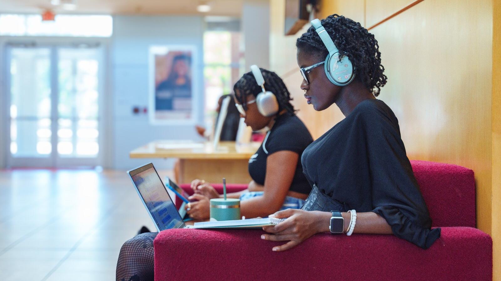 Students wearing headphones while concentrating on laptops