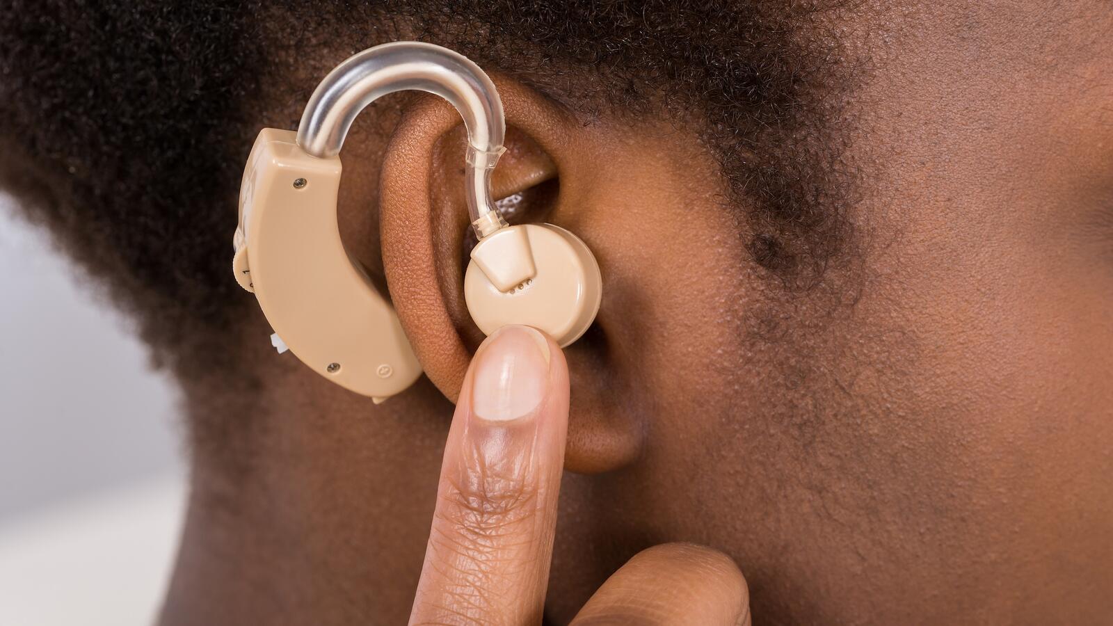 Woman holding hearing aid to ear
