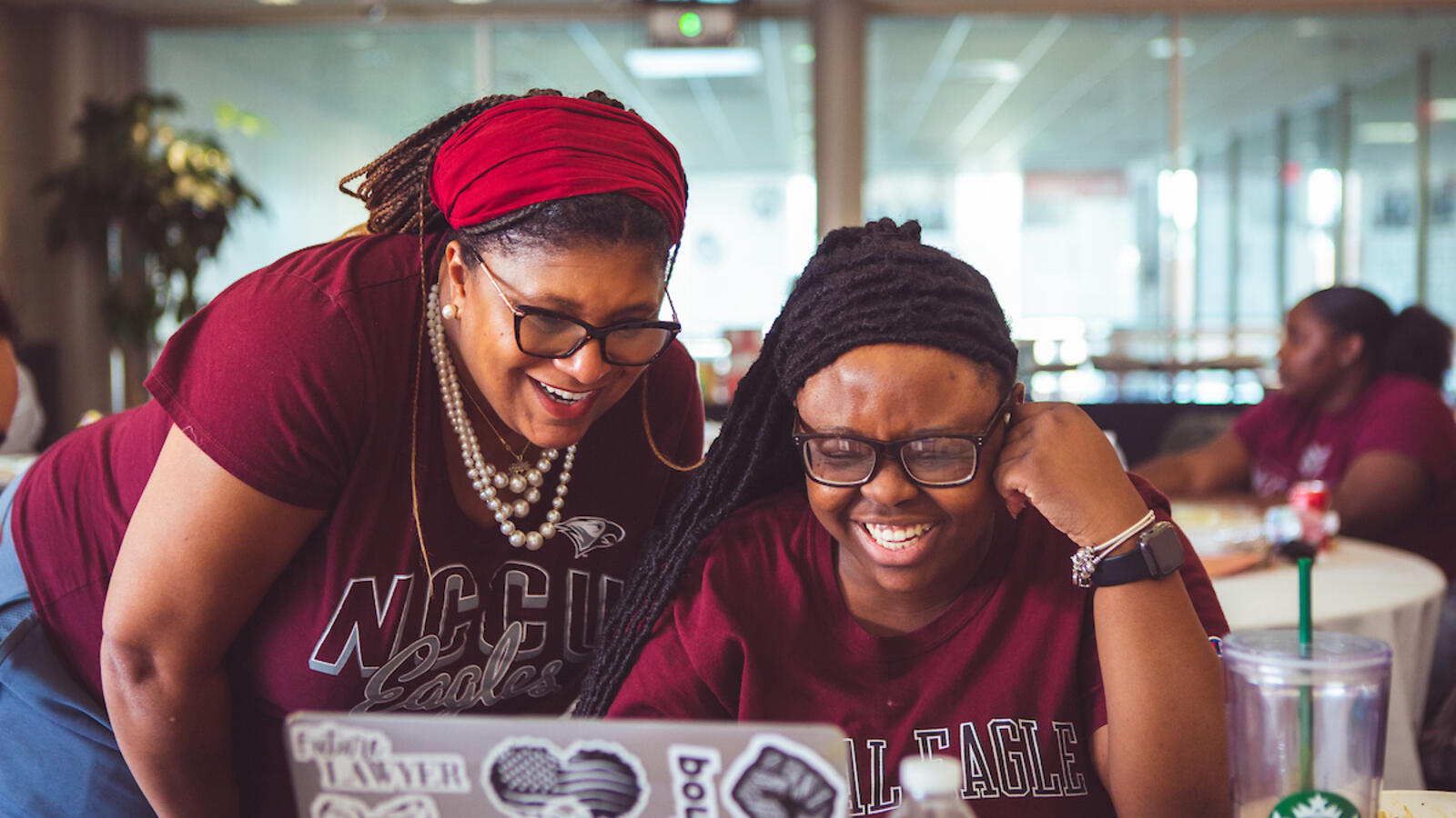Two people looking at a laptop and smiling