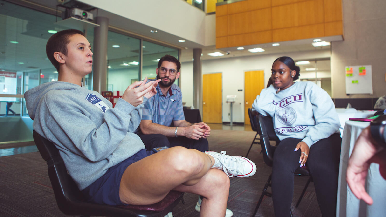 Three people sitting in chairs and having a discussion