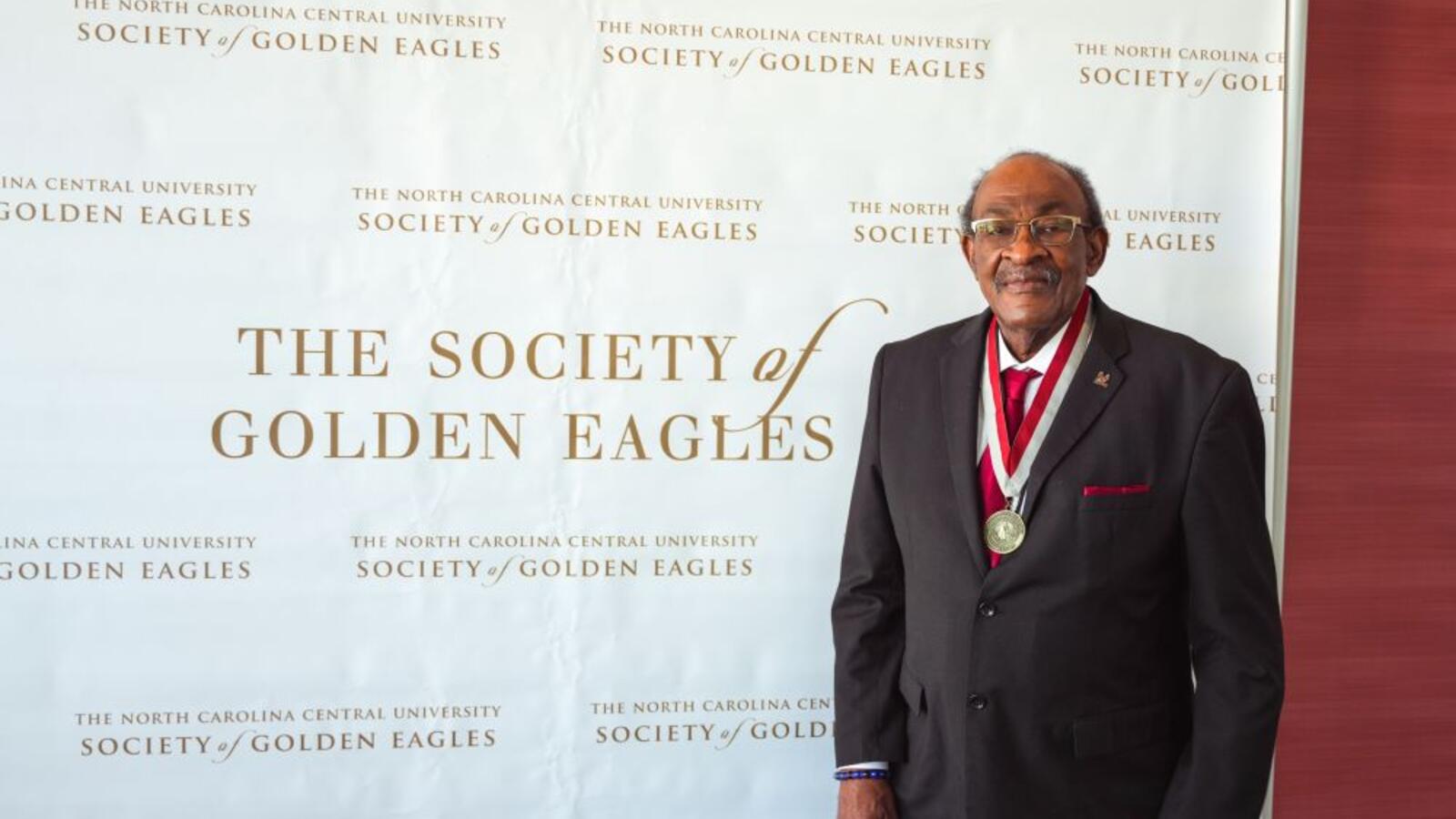 man standing in front of Society of Golden Eagles backdrop