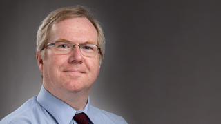 Photo of man with glasses and blue shirt.