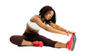 African American woman stretching her legs and touching her toees.