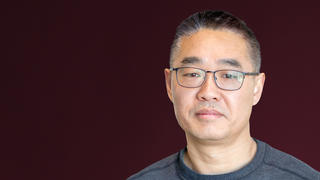 man with glasses, short dark hair and wearing a dark T shirt