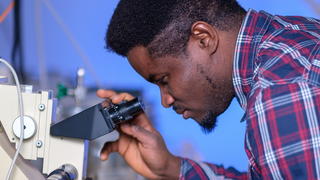 BRITE student looking into microscope