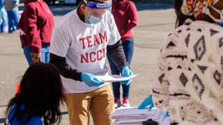 People standing under a tent preparing COVID-19 test kits