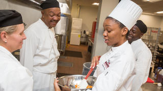 Hospitality students standing around in a kitchen. 