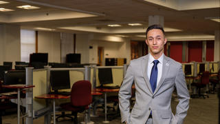 Computers surround male student in suit. 
