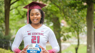 Volleyball player wearing graduation cap while holding volleyball.