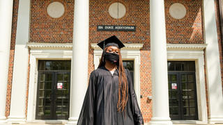 Graduate standing in front of historic building. 