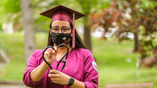 Nursing graduate holding medical equipment.