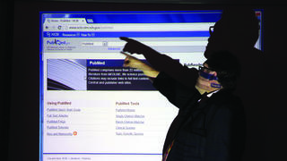 Man points to information on digital screen.