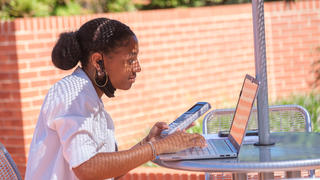 Student using a calculator in front of laptop