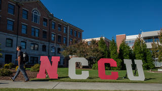 Student walking past NCCU letters