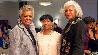 Three women facing the viewer at an event