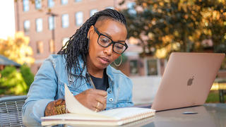 Student studying and taking notes outside