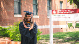 Graduate Taylor Dorsey Flowers in front of Dent Human Sciences Building