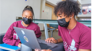 Two students using a laptop.